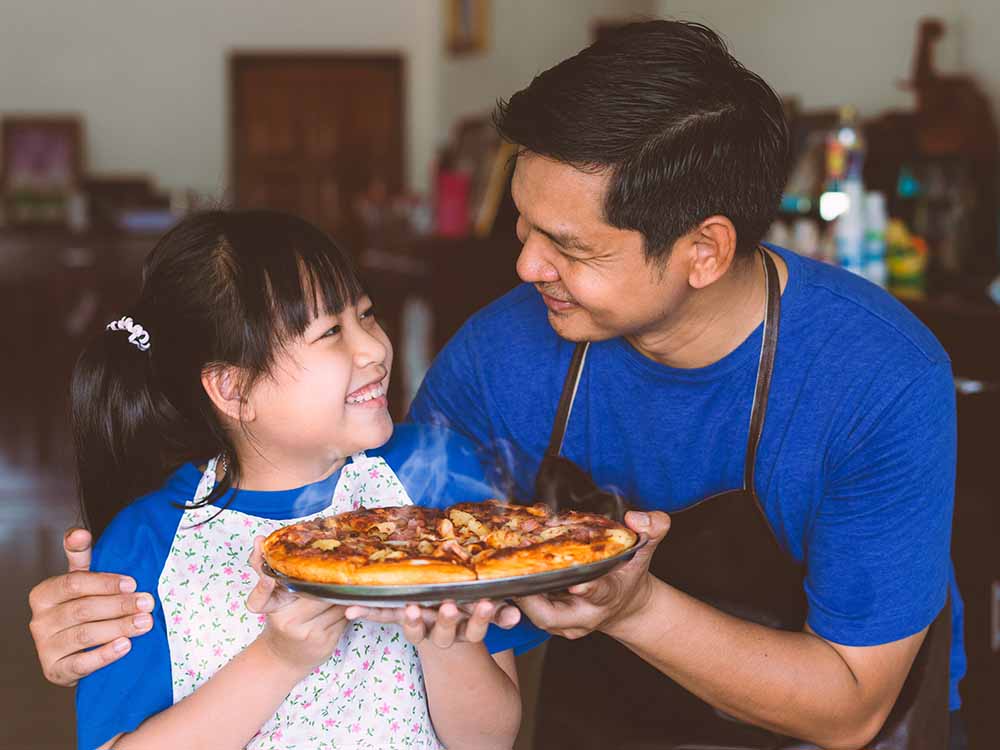 Daughter cooking homemade pizza with dad on Father's day.